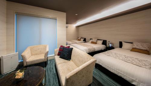 a hotel room with two beds and a couch at GRAND BASE Takamatsu in Takamatsu