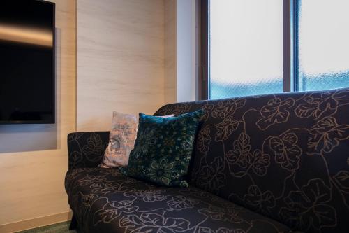 a couch with two pillows on it in a living room at GRAND BASE Takamatsu in Takamatsu