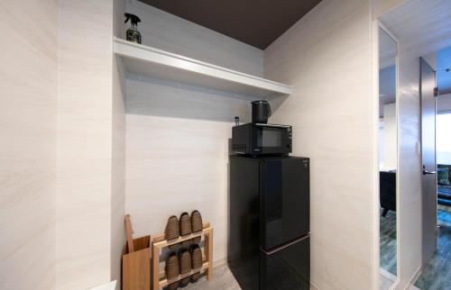 a room with a black refrigerator with a tv on top at GRAND BASE Takamatsu in Takamatsu