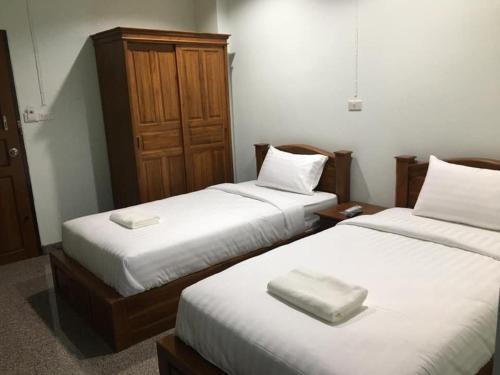 a room with two beds with white sheets and a wooden cabinet at โรงแรมคูณคีม in Nakhon Phanom