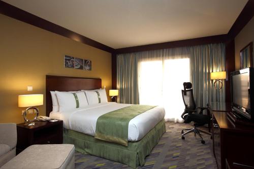 a hotel room with a large bed and a television at Holiday Inn Al Khobar - Corniche by IHG in Al Khobar