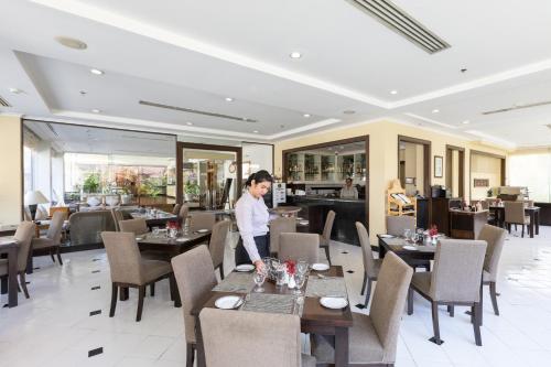 a woman standing at a table in a restaurant at Classic Kameo Hotel and Serviced Apartments, Sriracha in Si Racha