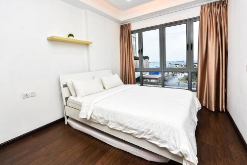 una camera con un letto bianco e una grande finestra di LOVINA 6-12 at Harbour Bay Residences a Nagoya