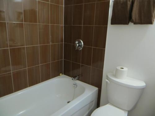 a bathroom with a white toilet and a bath tub at Sundown Motel in Watrous