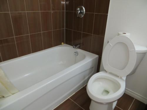 a bathroom with a white toilet and a bath tub at Sundown Motel in Watrous