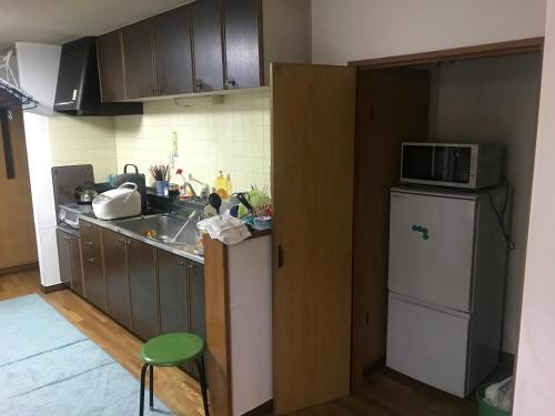 a kitchen with a sink and a microwave and a refrigerator at Otaru stay in Otaru