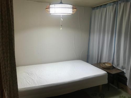 a small bedroom with a white bed and a light at Otaru stay in Otaru