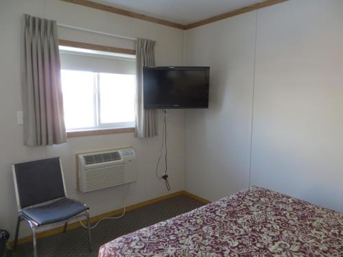 a bedroom with a bed and a tv and a chair at Sundown Motel in Watrous