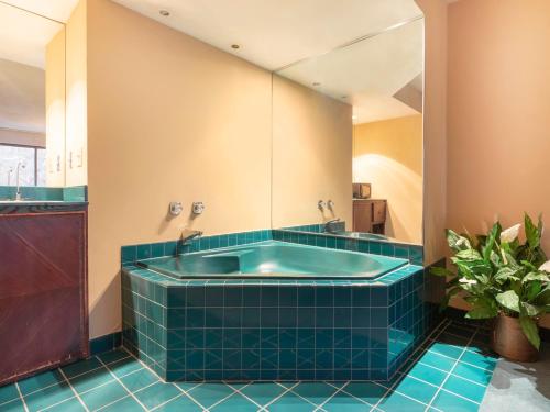 a tub in a bathroom with blue tile at Mansion View Inn & Suites in Springfield