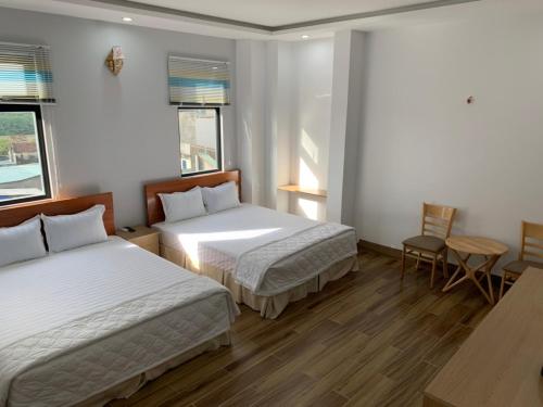 a bedroom with two beds and a table and chairs at Hotel Hiệp Thành in Tuy Hoa