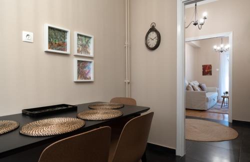 a dining room table with chairs and a clock on the wall at Absolute Athens XI in Athens