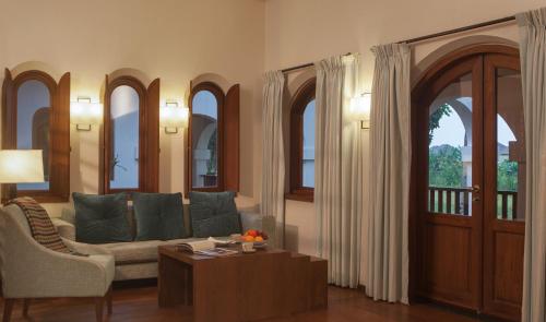 a living room with a couch and a table and windows at Sanctum Inle Resort in Nyaung Shwe