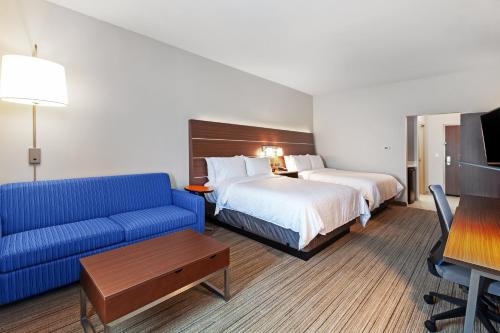 a hotel room with a bed and a blue couch at Holiday Inn Express & Suites - Tulsa Northeast - Owasso by IHG in Owasso