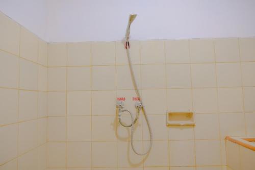eine Dusche in einem weiß gefliesten Bad in der Unterkunft OYO Life 2638 Hotel Raya in Sarangan