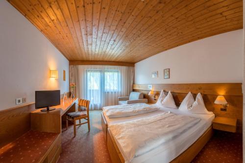 a hotel room with a large bed and a television at Hotel St. Pankraz in San Pancrazio dʼUltimo