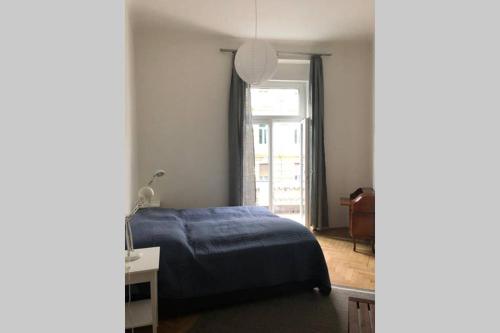 sypialnia z niebieskim łóżkiem i oknem w obiekcie Premium Apartment in Altstadtnähe w Grazu