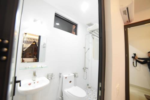 a man taking a picture of a bathroom with a toilet and sink at Asean Garden Homestay Hue in Hue
