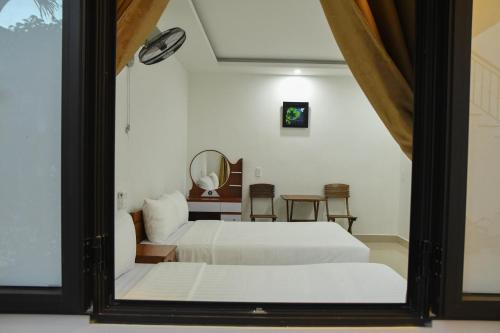 a bedroom with two beds and a table and a mirror at Asean Garden Homestay Hue in Hue