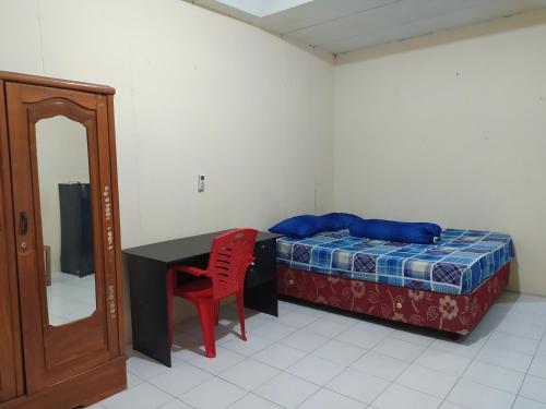 Schlafzimmer mit einem Bett, einem Schreibtisch und einem roten Stuhl in der Unterkunft OYO 3116 Batu Putih Homestay in Makassar