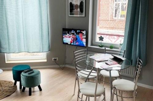 ein Esszimmer mit einem Tisch, Stühlen und einem TV in der Unterkunft Caudry : Bel appartement plein centre in Caudry