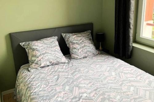 a bed with two pillows and a comforter at Caudry : Bel appartement plein centre in Caudry