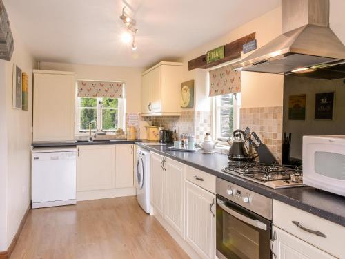 a kitchen with white cabinets and a stove top oven at Mimi's Cottage in Liskeard