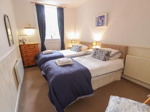een slaapkamer met 2 bedden en blauwe dekens bij Turret Cottage in Prestonpans