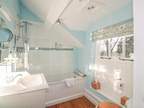 La salle de bains blanche est pourvue d'un lavabo et d'une douche. dans l'établissement The Hayloft, à Bromyard