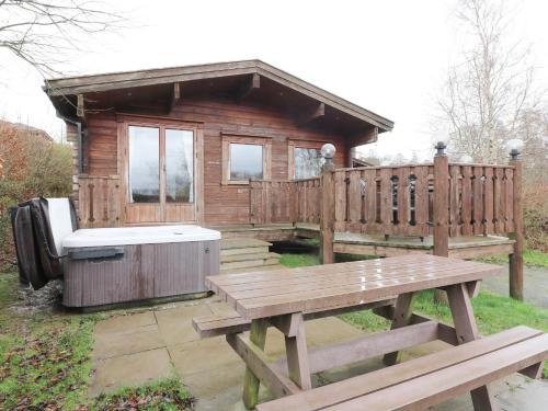 a wooden cabin with a bench and a hot tub at Barn Owl Lodge in Rhayader