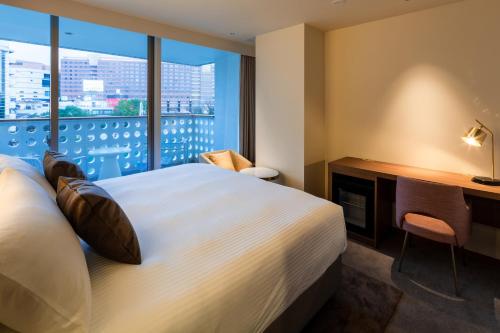 a hotel room with a bed and a desk and a window at The OneFive Villa Fukuoka in Fukuoka