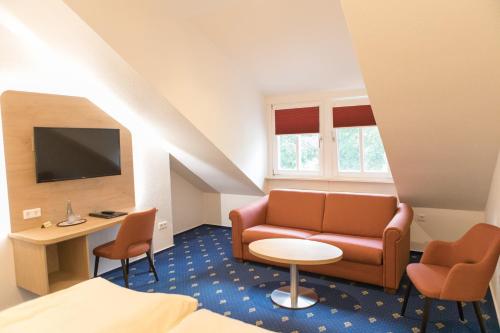 ein Hotelzimmer mit einem Sofa, einem Tisch und Stühlen in der Unterkunft Hotel Restaurant Lathener Marsch in Lathen