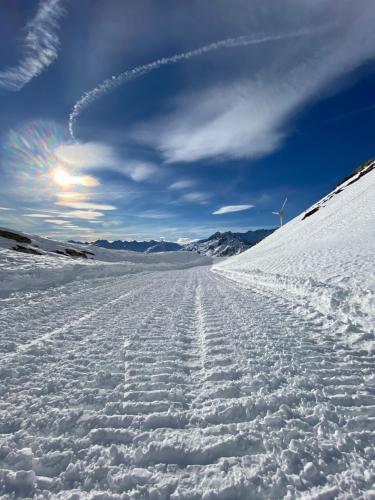 a snow covered road with the sun in the background at Privatzimmer / bed & breakfast in Andermatt