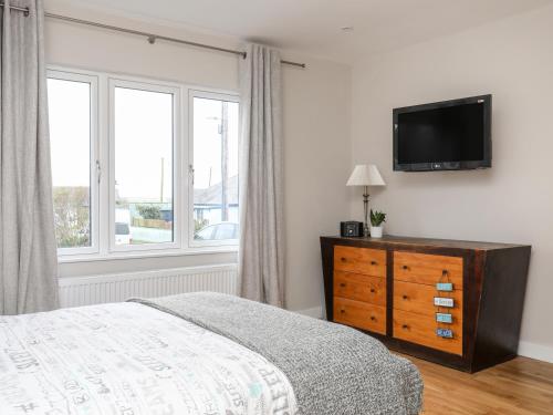 a bedroom with a bed and a television on a wall at Laneton in Rhosneigr