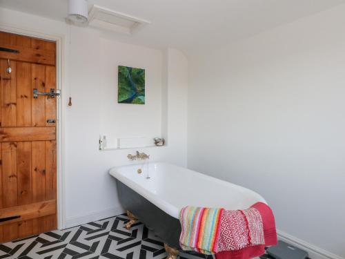 a bath tub in a bathroom with a wooden door at Holly Tree Cottage in Chester