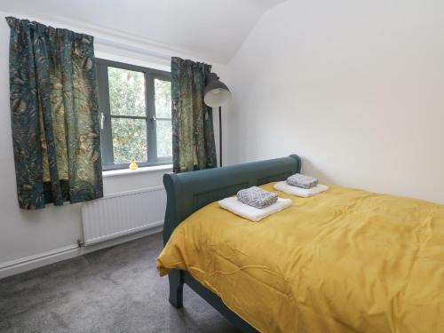 a bedroom with a yellow bed and a window at Holly Tree Cottage in Chester