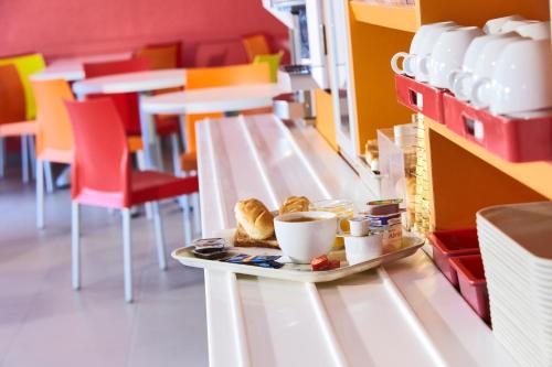 einen Teller mit Essen und eine Tasse Kaffee auf dem Tisch in der Unterkunft HECO Colmar Nord - ex Première Classe in Houssen