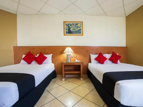 Habitación de hotel con 2 camas con almohadas rojas en Hotel Zadapi, en Oaxaca City