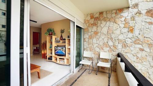 Habitación con pared de piedra y 2 sillas en Meridian 107 condo, en Playa del Carmen