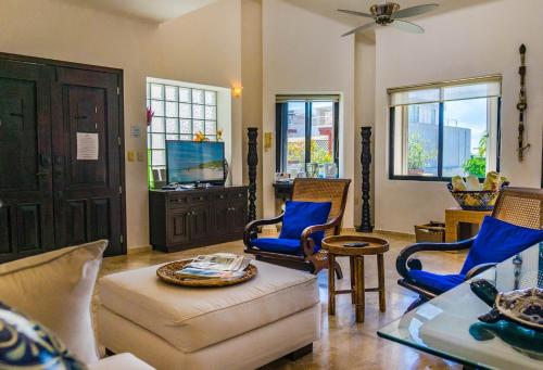 a living room with chairs and a couch and a tv at Royal Palms 10 condo in Playa del Carmen