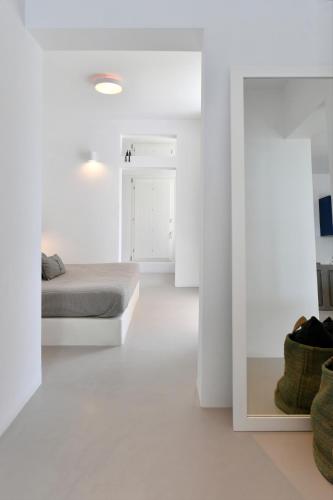 a white room with a bed and a mirror at Thiro Santorini in Fira