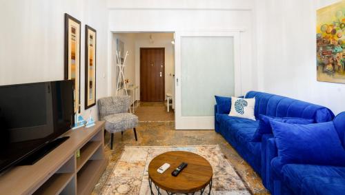 un salon avec un canapé bleu et une télévision dans l'établissement Unique apartment in Glyfada center, à Athènes