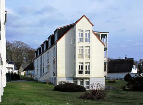 un edificio blanco con techo de gambrel en Ferienwohnung strandnah mit Balkon, en Ostseebad Koserow