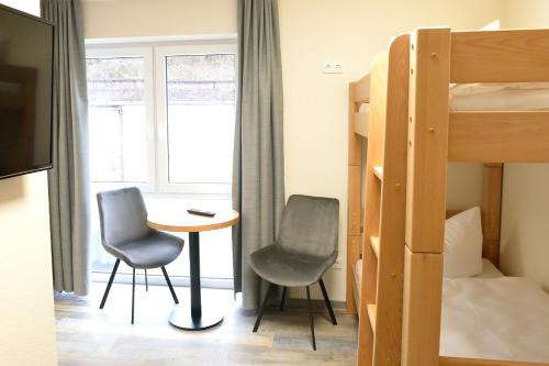 a bedroom with a bunk bed and two chairs and a table at Hostel & Pension Alte Brauerei in Eisenach