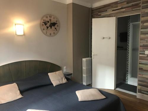 - une chambre dotée d'un lit avec une horloge murale dans l'établissement Hotel Bernieres, à Caen