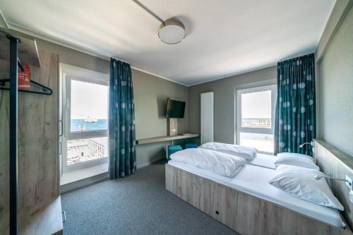 a bedroom with a large bed and two windows at WIROtel Warnemünde in Warnemünde