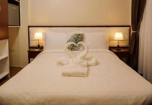 a bed with towels arranged in the shape of a heart at Amigos Dauin Hostel in Dauin