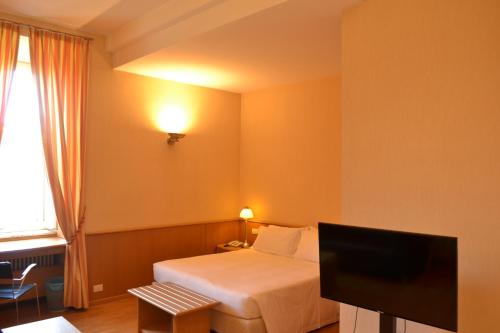 a hotel room with a bed and a flat screen tv at Dynasty Suites Downtown Apartments in Turin