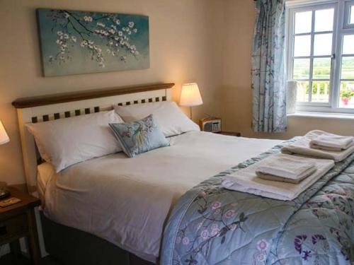 a bedroom with a large bed with towels on it at Derwent Cottage in Malton