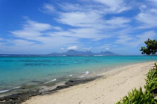 a beach with the ocean and mountains in the background at Sunset Beach Carlton- Tahiti - beachfront luxury residence & pool - 4 pers in Punaauia