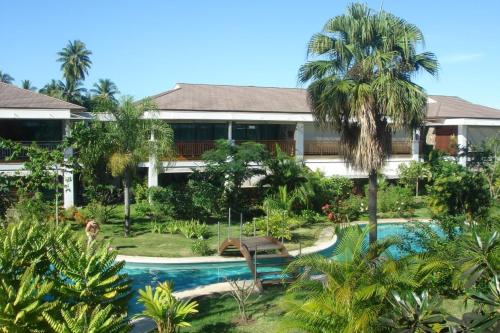 a resort with a swimming pool and palm trees at Sunset Beach Carlton- Tahiti - beachfront luxury residence & pool - 4 pers in Punaauia